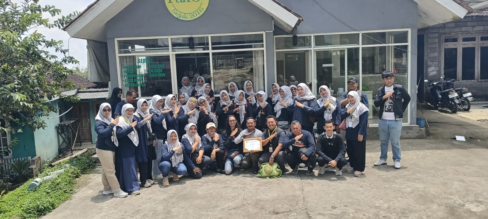 Rombongan berfoto di depan tempat usaha lokal.